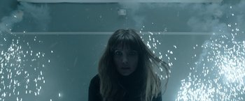 Movie still from “Malignant” (2021), directed by James Wan – A woman with long brown hair standing next to a wall; Close Up shot, Low angle