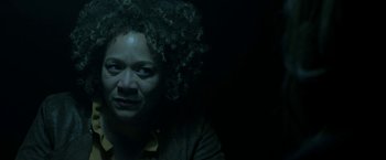 Movie still from “Malignant” (2021), directed by James Wan – A woman with curly black hair sitting in a dark room; Close Up shot, Low angle