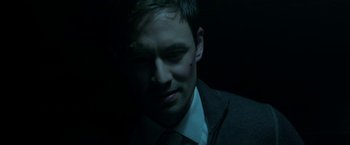 Movie still from “Malignant” (2021), directed by James Wan – A person wearing a suit and tie; Close Up shot, Low angle