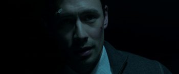 Movie still from “Malignant” (2021), directed by James Wan – A person wearing a suit and tie; Close Up shot, High angle