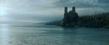 Movie still from “Malignant” (2021), directed by James Wan – A castle on top of a hill near a body of water; Extreme Wide shot, High angle