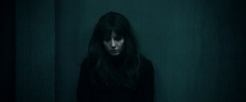 Movie still from “Malignant” (2021), directed by James Wan – A woman with long hair is standing against a wall; Close Up shot, Overhead angle
