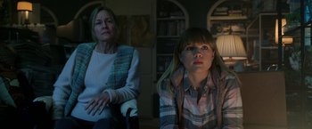 Movie still from “Malignant” (2021), directed by James Wan – Two women sitting next to each other in a living room; Medium shot, Over the shoulder angle