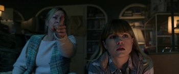 Movie still from “Malignant” (2021), directed by James Wan – A woman and a girl are watching something on a tv screen; Medium shot, Over the shoulder angle