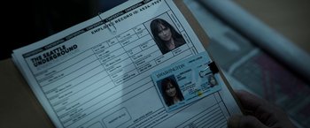 Movie still from “Malignant” (2021), directed by James Wan – An employee record id is displayed on a document; Extreme Close Up shot, High angle