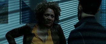 Movie still from “Malignant” (2021), directed by James Wan – A person with curly hair wearing a jacket; Close Up shot, Over the shoulder angle