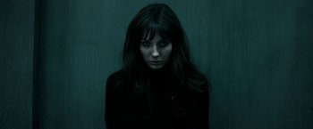 A woman with long black hair is staring at the camera
