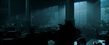 Movie still from “Malignant” (2021), directed by James Wan – A person sitting at a table in a dark room; Wide shot, Low angle