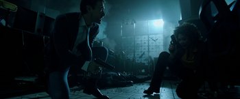 Movie still from “Malignant” (2021), directed by James Wan – A man in a suit and tie holding a gun in a room; Wide shot, Low angle