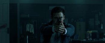 Movie still from “Malignant” (2021), directed by James Wan – A man in a suit and tie holding a gun; Close Up shot, Low angle