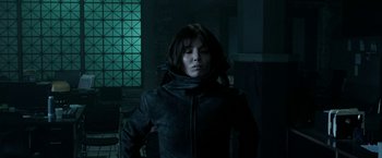 Movie still from “Malignant” (2021), directed by James Wan – A woman wearing a black jacket standing next to a window; Medium shot, Low angle