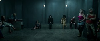 Movie still from “Malignant” (2021), directed by James Wan – A group of people sitting on a bench in front of a wall; Wide shot, Overhead angle