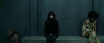 Movie still from “Malignant” (2021), directed by James Wan – A woman sitting on a ledge in front of a concrete wall; Medium shot, High angle