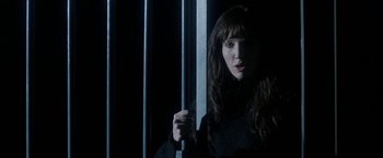 Movie still from “Malignant” (2021), directed by James Wan – A woman holding a metal bar in front of a window; Medium shot, Low angle