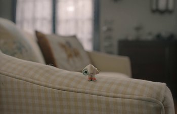 Movie still from “Marcel the Shell with Shoes On” (2021), directed by Dean Fleischer Camp – A toy bird sitting on top of a couch; Extreme Close Up shot, High angle