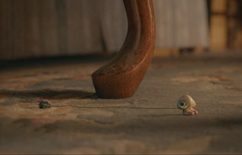 Movie still from “Marcel the Shell with Shoes On” (2021), directed by Dean Fleischer Camp – A snail is sitting on the ground next to a wooden handle; Extreme Close Up shot, High angle