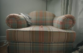 Movie still from “Marcel the Shell with Shoes On” (2021), directed by Dean Fleischer Camp – A plaid chair with a blanket on top of it; Wide shot, High angle
