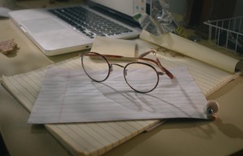 Movie still from “Marcel the Shell with Shoes On” (2021), directed by Dean Fleischer Camp – A pair of glasses sitting on top of a piece of paper; Extreme Close Up shot, High angle