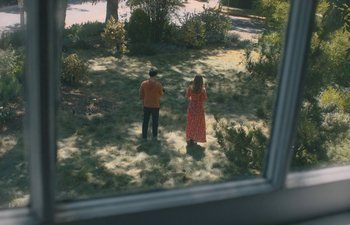 Movie still from “Marcel the Shell with Shoes On” (2021), directed by Dean Fleischer Camp – Two people standing in the grass looking out a window; Extreme Wide shot, High angle