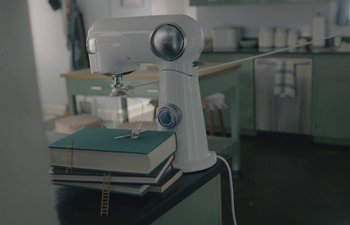 Movie still from “Marcel the Shell with Shoes On” (2021), directed by Dean Fleischer Camp – A white sewing machine sitting on top of a table; Extreme Close Up shot, Overhead angle