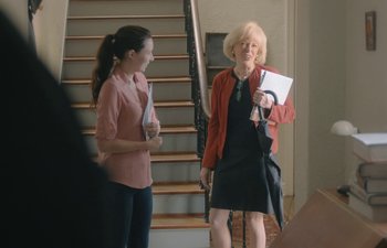 Movie still from “Marcel the Shell with Shoes On” (2021), directed by Dean Fleischer Camp – Two women standing next to each other in front of a staircase; Medium shot, Over the shoulder angle