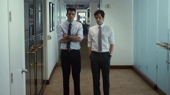 Movie still from “Margin Call” (2011), directed by J.C. Chandor – Two young men standing next to each other in an office hallway; Medium shot, Low angle