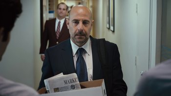 Movie still from “Margin Call” (2011), directed by J.C. Chandor – A man in a suit and tie holding a box of papers; Medium shot, Over the shoulder angle