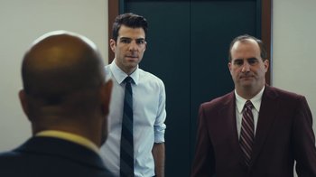 Movie still from “Margin Call” (2011), directed by J.C. Chandor – A man in a white shirt and a red tie standing next to another man in a suit and tie; Medium shot, Over the shoulder angle