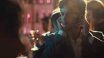 Movie still from “Margin Call” (2011), directed by J.C. Chandor – A man holding a glass of wine while talking on the phone; Close Up shot, Over the shoulder angle