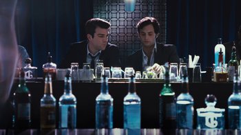 Movie still from “Margin Call” (2011), directed by J.C. Chandor – A couple of men sitting in front of some bottles; Medium shot, Over the shoulder angle