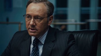 Movie still from “Margin Call” (2011), directed by J.C. Chandor – A man in a suit and tie sitting in a chair; Close Up shot, Over the shoulder angle