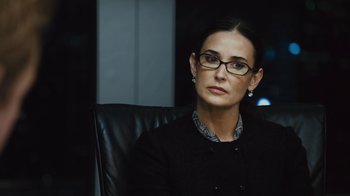 Movie still from “Margin Call” (2011), directed by J.C. Chandor – A woman sitting in an office chair wearing glasses; Close Up shot, Over the shoulder angle