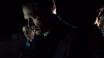 Movie still from “Margin Call” (2011), directed by J.C. Chandor – A man in a black suit is smoking a cigarette; Close Up shot, Low angle