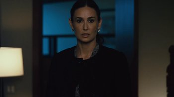 Movie still from “Margin Call” (2011), directed by J.C. Chandor – A woman in a black jacket standing in a dark room; Close Up shot, Over the shoulder angle