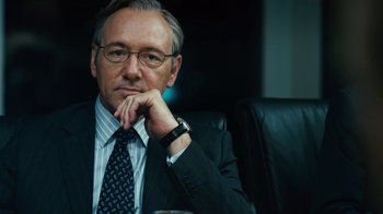 Movie still from “Margin Call” (2011), directed by J.C. Chandor – A man in a suit and tie sitting in a chair; Close Up shot, Low angle