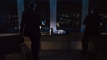 Movie still from “Margin Call” (2011), directed by J.C. Chandor – Two people standing in front of a large window at night; Wide shot, Over the shoulder angle