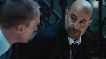 Movie still from “Margin Call” (2011), directed by J.C. Chandor – A man in a suit and tie talking to another man in a suit and tie; Close Up shot, Over the shoulder angle
