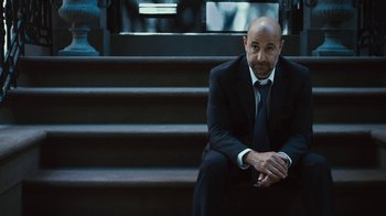 Movie still from “Margin Call” (2011), directed by J.C. Chandor – A man in a suit and tie sitting on some steps; Medium shot, Low angle