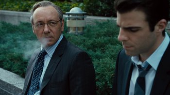 Movie still from “Margin Call” (2011), directed by J.C. Chandor – A man smoking a cigarette next to another man in a suit; Close Up shot, Over the shoulder angle