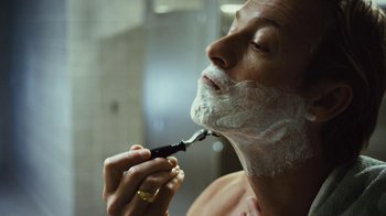 Movie still from “Margin Call” (2011), directed by J.C. Chandor – A man shaving his face with a razor in a bathroom; Close Up shot, Low angle