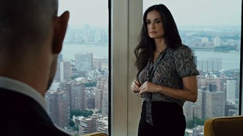 Movie still from “Margin Call” (2011), directed by J.C. Chandor – A woman standing in front of a window with a city view; Medium shot, Over the shoulder angle