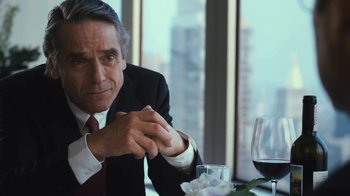 Movie still from “Margin Call” (2011), directed by J.C. Chandor – A person sitting at a table with a glass of red wine; Close Up shot, Over the shoulder angle