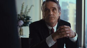Movie still from “Margin Call” (2011), directed by J.C. Chandor – A man in a suit and tie sitting at a table; Close Up shot, Over the shoulder angle