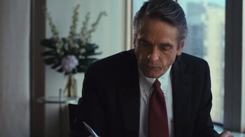 Movie still from “Margin Call” (2011), directed by J.C. Chandor – An older man wearing a suit and tie looking down at a piece of paper in front of him; Close Up shot, Over the shoulder angle