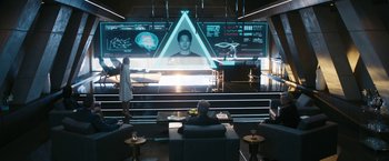 Movie still from “Maze Runner: The Death Cure” (2018), directed by Wes Ball – A man and a woman are sitting in front of a large screen; Wide shot, High angle