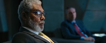 Movie still from “Maze Runner: The Death Cure” (2018), directed by Wes Ball – A man in a suit and tie sitting in front of another man; Close Up shot, Over the shoulder angle