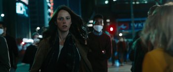 Movie still from “Maze Runner: The Death Cure” (2018), directed by Wes Ball – A woman walking down a street next to a man wearing a face mask; Medium shot, Over the shoulder angle
