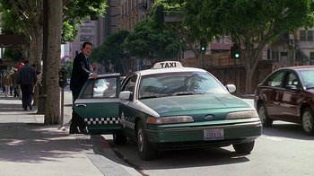 Movie still from “Meet the Fockers” (2004), directed by Jay Roach – A man standing next to a green taxi cab on the side of the road; Wide shot, High angle