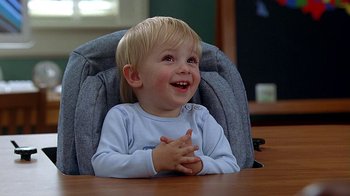 Movie still from “Meet the Fockers” (2004), directed by Jay Roach – A little boy sitting at a table with his hands clasped together; Medium shot, High angle