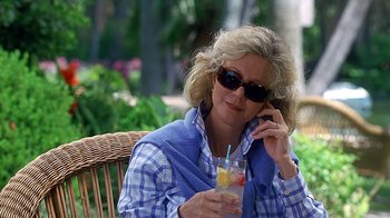 Movie still from “Meet the Fockers” (2004), directed by Jay Roach – A woman sitting on a chair talking on a cell phone and holding a drink; Medium shot, Over the shoulder angle